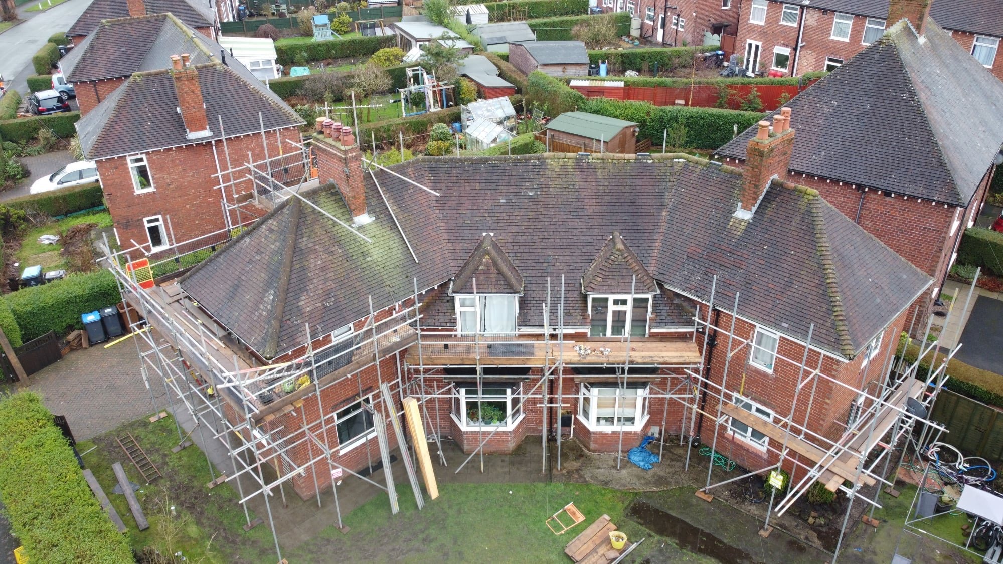 Aerial view of a brick semi-detached house fully scaffolded for roof work